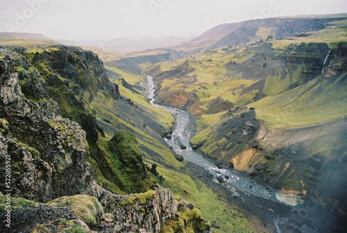 Mountain river flowing down a valley between mountain ranges in Iceland. Grainy film in the style of old photos. High quality photo © Dima Anikin