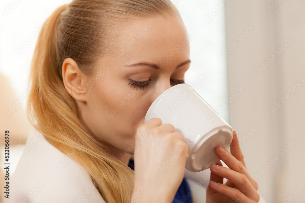 Woman lying on sofa under blanket drinking tea Woman lying on sofa under blanket drinking tea