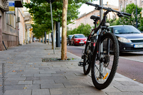 Bicycle secured to a pole on a sidewalk in a town