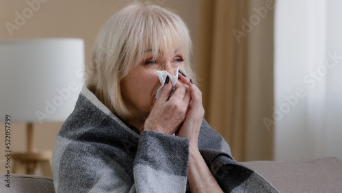Foto Close up ill sick old blonde grandmother 60s woman covered in warm blanket at ho