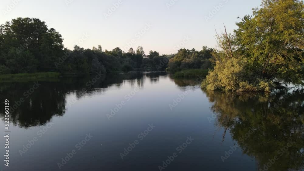 Calm water from a river with reflection of the trees and golden dawn light. Calm water from a river with reflection of the trees and golden dawn light.
