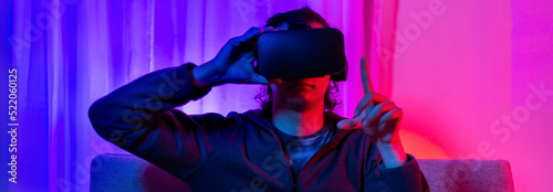 Man wearing virtual reality glasses is playing a 3D game with excitement, Bluetooth Remote Controller, VR, Future games, Gadgets, Technology, Red and blue background, VR game concept.