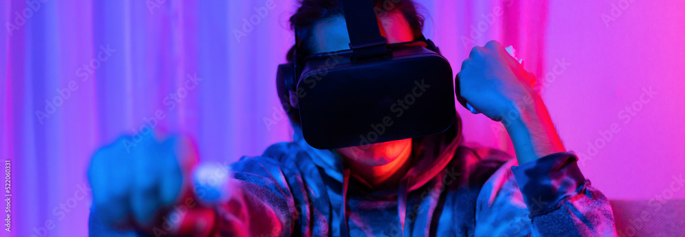 Naklejka premium Man wears virtual reality glasses and uses joystick to play games with fun, VR, Future games, Technology, Red and blue background, Touch Controller, Bluetooth Remote Controller, VR game concept.