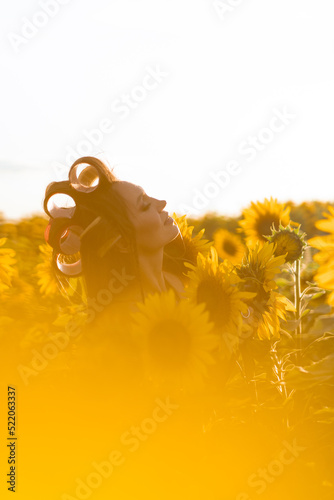 Young beautiful woman with curlers on her hair in a field of sunflowers. Fashion. photo