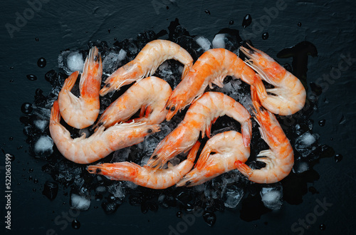 Food flat background, shrimp and ice on dark stone, top view