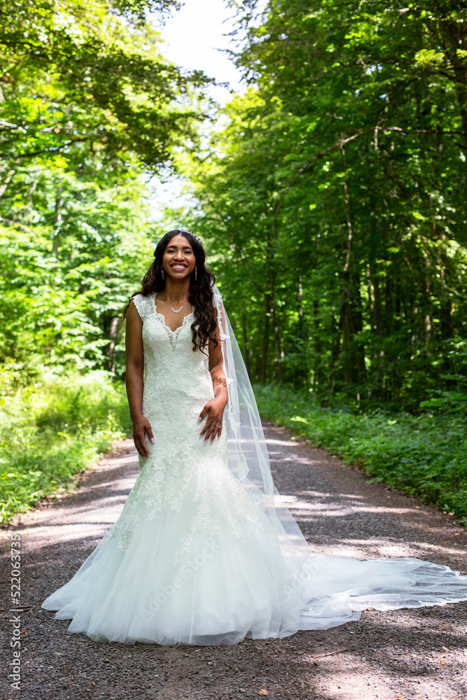 beautiful african-american bride standing in a white gown outdoors in nature