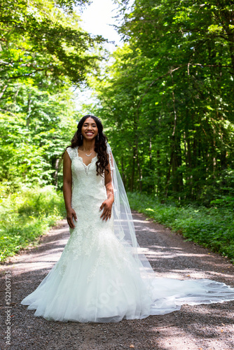 beautiful african-american bride standing in a white gown outdoors in nature