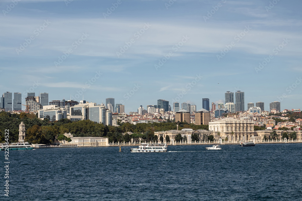 View of boats on Bosphorus, historical Dolmabahce Palace and European side of Istanbul. It is a sunny summer day.
