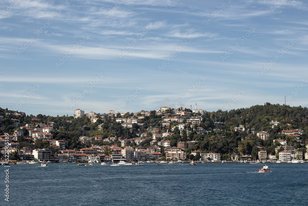 View of yachts and cruise tour boats on Bosphorus and Bebek neighborhood on European side of Istanbul. It is a sunny summer day. Beautiful travel scene.