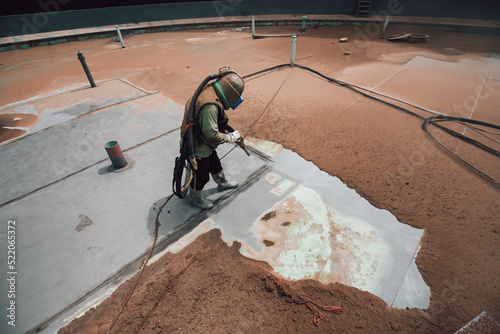 Foto Male worker surface corrosion plate preparation by sandblasting bounce off of tank top deck
