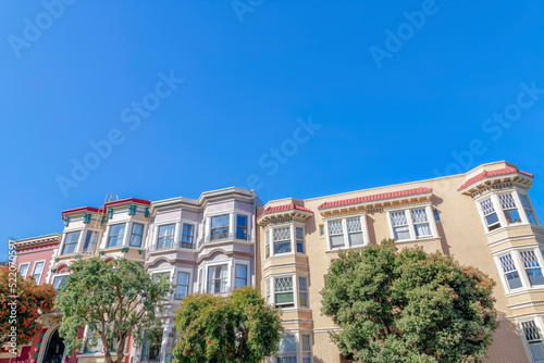 Rowhouses with bay windows and apartment building with sash windows in San Francisco, CA