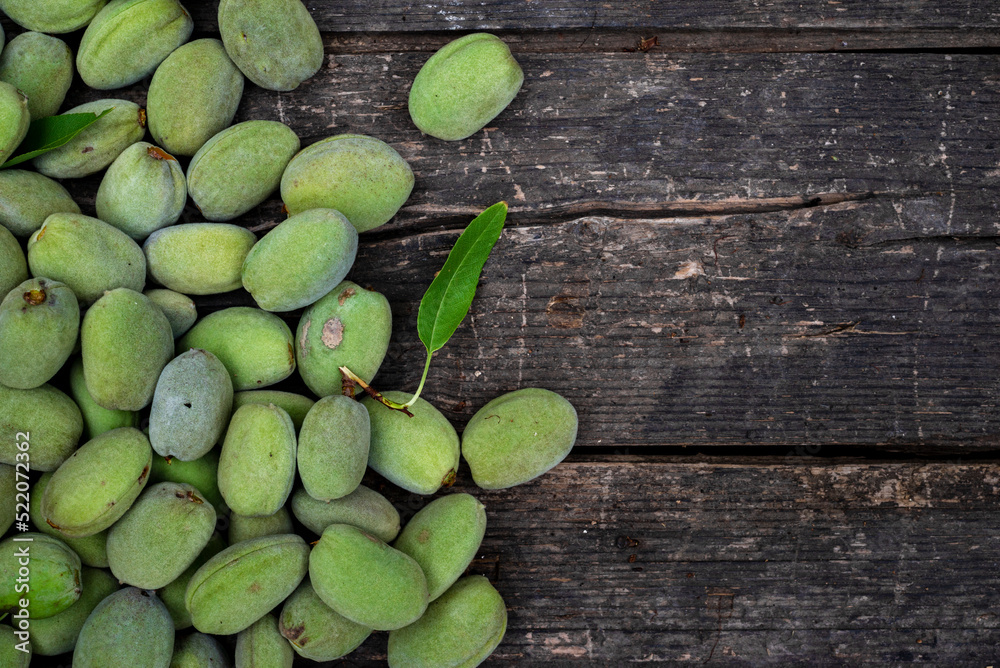 Green almonds background   fresh raw unripe wooden rustic table blurred garden background leaves, Top view concept with copy space shell  tree branch pattern texture