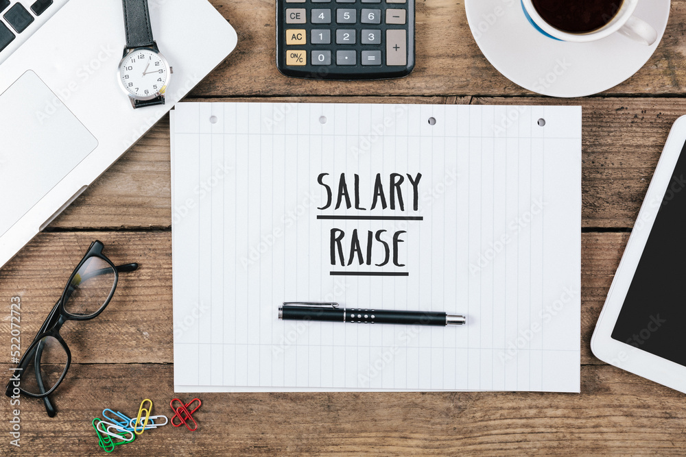 Naklejka premium Salary Raise written in notepad on office desk with computer technology, high angle
