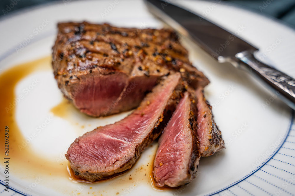 Sliced medium rare beef steak on a white plate
