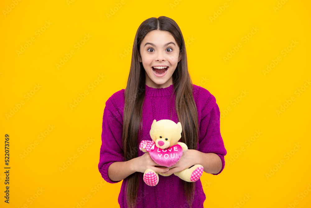 Excited face. Teen girl in casual clothes hold soft toy for birthday on yellow background. Kid spending time with her toys. Amazed expression, cheerful and glad. Excited face. Teen girl in casual clothes hold soft toy for birthday on yellow background. Kid spending time with her toys. Amazed expression, cheerful and glad.