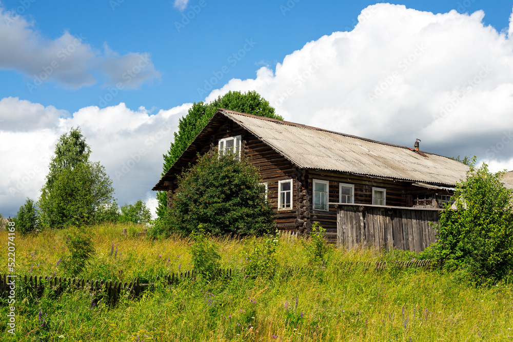 Rustic log old wooden house in village on hill on natural background of sky clouds grass trees Rustic log old wooden house in village on hill on natural background of sky clouds grass trees