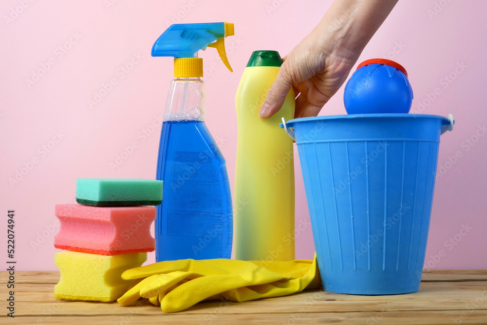 plastic bucket with brushes, gloves and detergents in the kitchen, basket with cleaning items plastic bucket with brushes, gloves and detergents in the kitchen, basket with cleaning items
