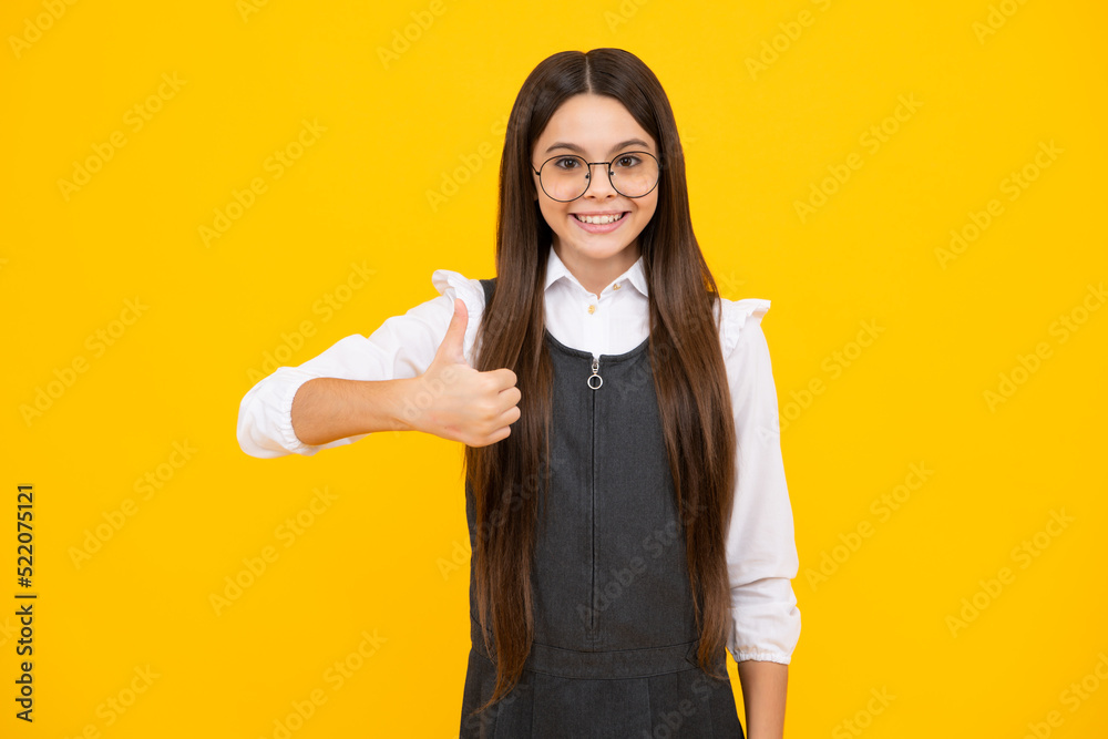 Teenager child girl 12, 13, 14 year old doing thumbs up gesture. Cheerful teenager girl showing thumbs up sign, isolated on yellow background. Happy girl face, positive and smiling emotions. Teenager child girl 12, 13, 14 year old doing thumbs up gesture. Cheerful teenager girl showing thumbs up sign, isolated on yellow background. Happy girl face, positive and smiling emotions.