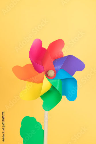 Coloured pinwheel on yellow background. Copy space. Vertical photo. © castellanos80