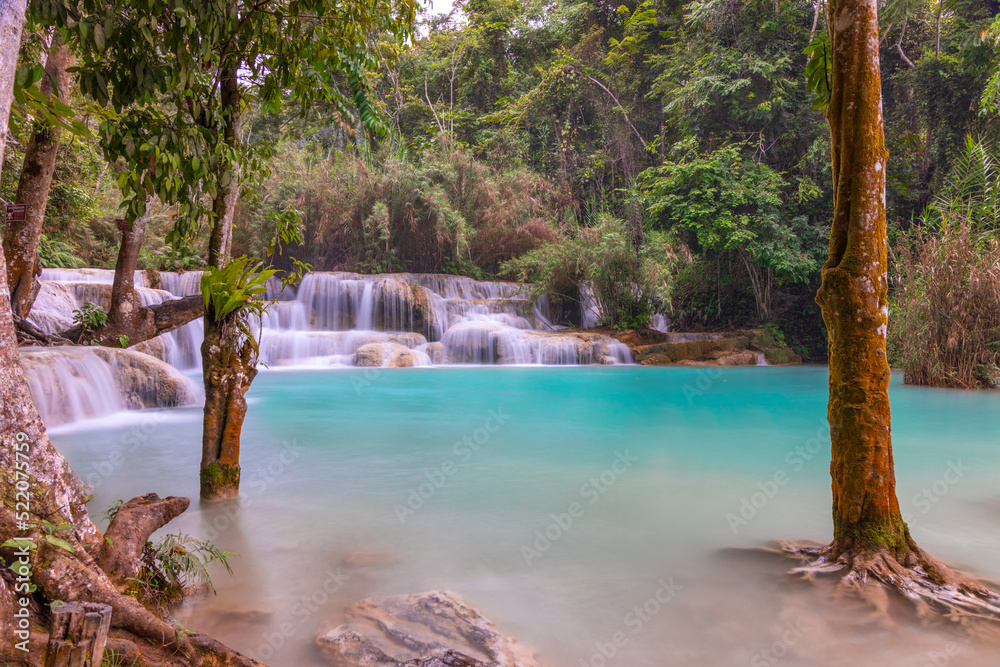 Magical turquoise blue colours of Kuang Si waterfalls Luang Prabang Laos. these waterfalls in the Mountains of Luang Prabang Laos flow all year round in the natural national park rainforest 