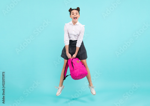 Back to school. Teenager schoolgirl in school uniform with bagpack. Jump and run. School children on isolated studio background. Amazed teenager. Excited teen girl.