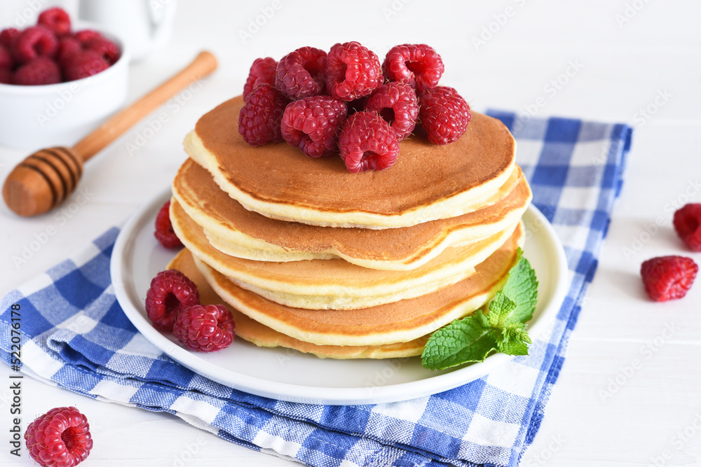 Homemade pancakes with raspberries and jam for breakfast on a white background