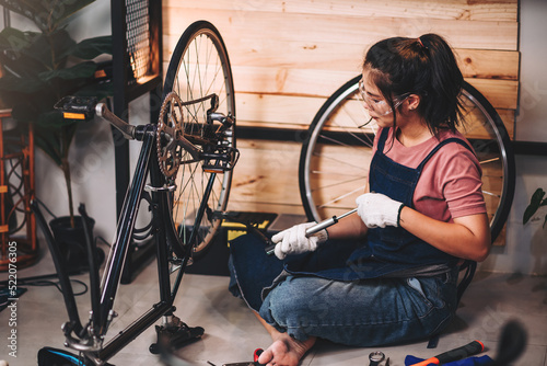 Beautiful asian woman repairman girl ,bike maintenance with happy and replace a bike chain, self bike workshop at home.