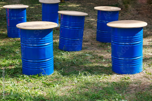 Tables made of blue barrels. Blue barrels are standing on the grass. Outdoor outdoor outdoor cafe. Festival, holiday.