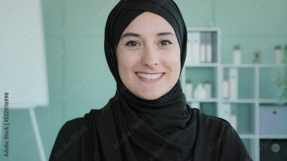 Close up moving shooting Islamic Muslim woman smiling toothy in office carefree businesswoman female boss leader student girl manager entrepreneur in company space looking camera with smile headshot Close up moving shooting Islamic Muslim woman smiling toothy in office carefree businesswoman female boss leader student girl manager entrepreneur in company space looking camera with smile headshot
