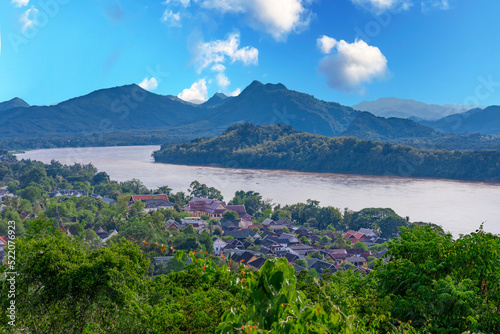 Luang Prabang Laos, beautiful river surrounded by lush green mountains and lovely historical houses