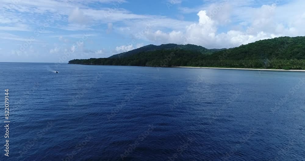 Aerial shot of a zodiac passing in front of a tropical paradise island Aerial shot of a zodiac passing in front of a tropical paradise island
