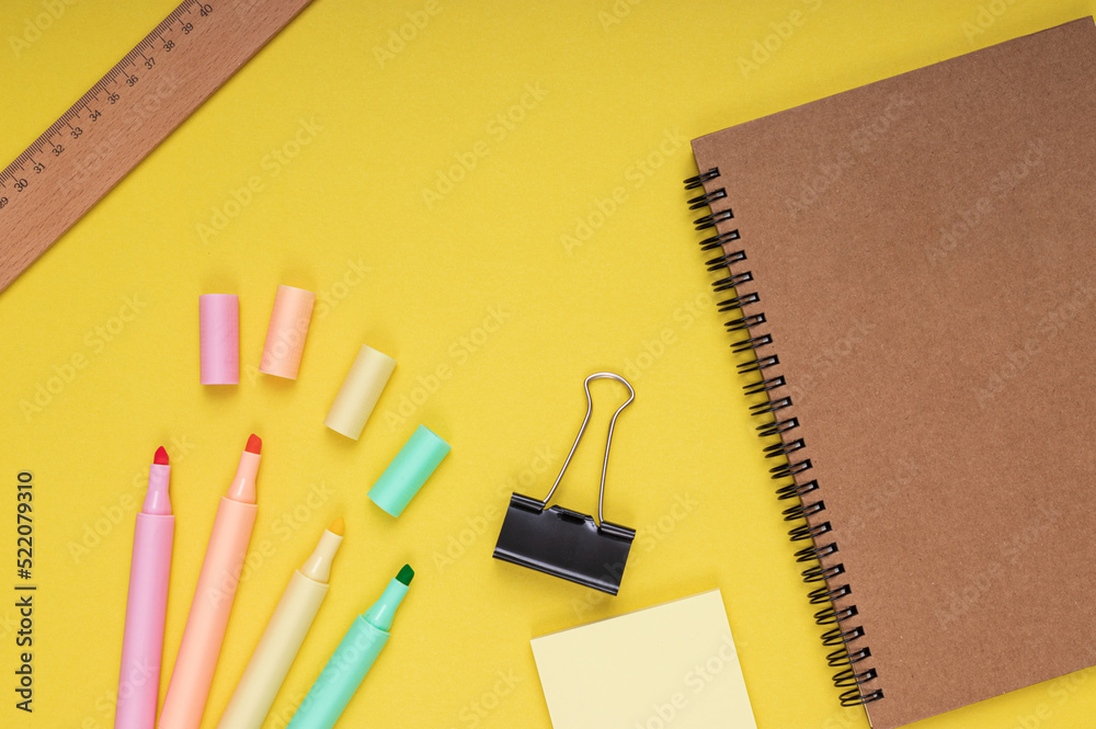 Notebook, colored pencils, note paper and clamp, ruler. back to school. Isolated yellow background Notebook, colored pencils, note paper and clamp, ruler. back to school. Isolated yellow background