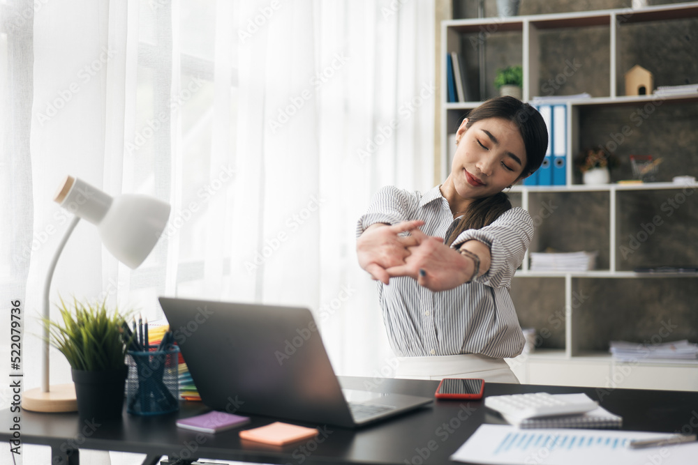 Young business women is relaxing and stretching while working on laptop in office space. Young business women is relaxing and stretching while working on laptop in office space.