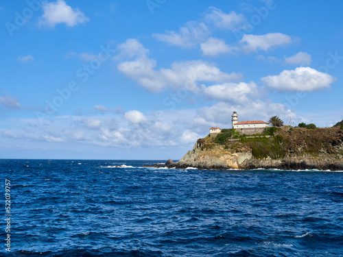 Lighthouse in the blue water of the Cantabrian sea. Cudillero, a charming and picturesque fishing village in Asturias, Spain