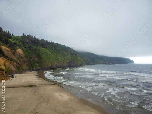 Calm seascape. The white waves of the ocean float on the sandy shore. Long mountain range with pine forest. The beauty of nature, relaxation. relaxation, tourism, travel, ecology.
