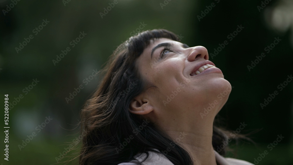 Happy woman looks up to Sky smiling. A contemplative hispanic girl having FAITH feeling JOY