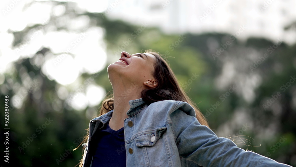 Happy woman celebrating achievement raising arms in the air feeling FREEDOM. Joyful person standing outside in nature Happy woman celebrating achievement raising arms in the air feeling FREEDOM. Joyful person standing outside in nature