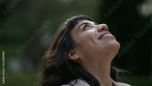 Happy woman looks up to Sky smiling. A contemplative hispanic girl having FAITH feeling JOY photo