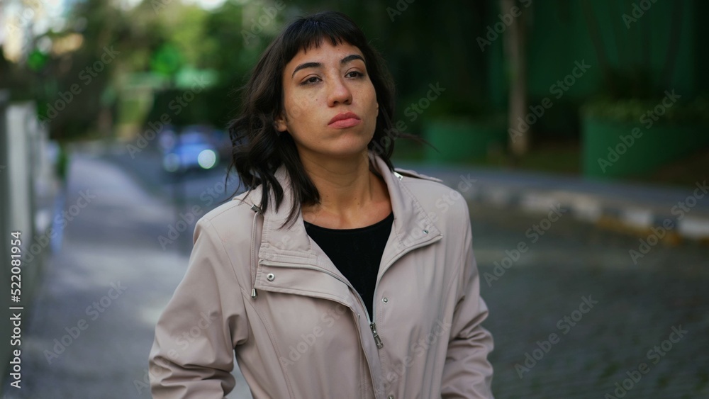 One pensive hispanic young woman walking outside in street. Confident girl walks forward