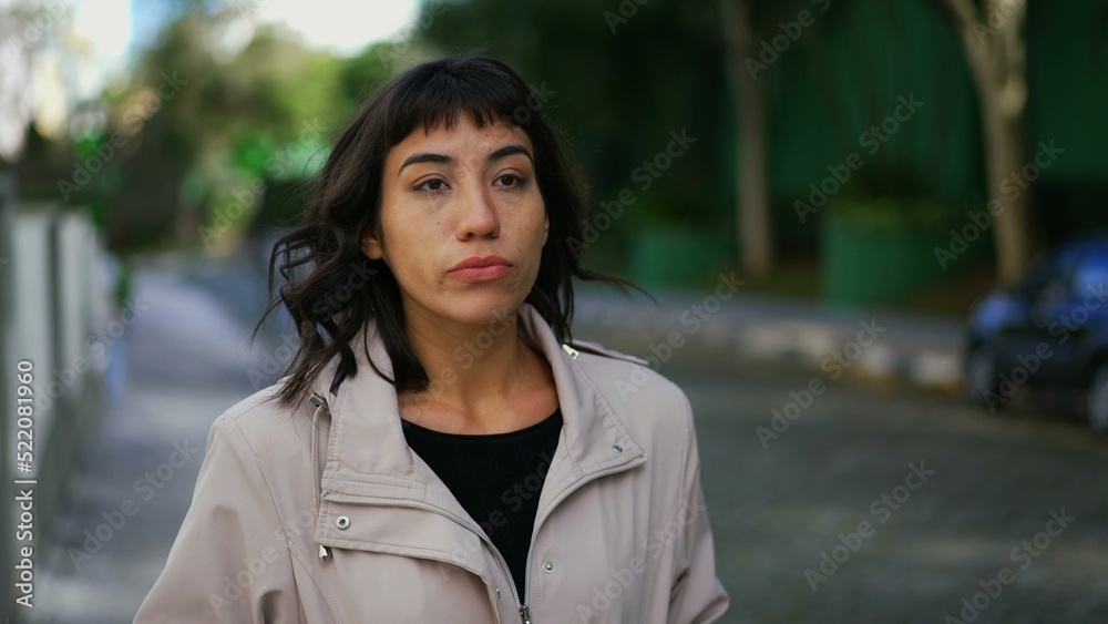 One pensive hispanic young woman walking outside in street. Confident girl walks forward