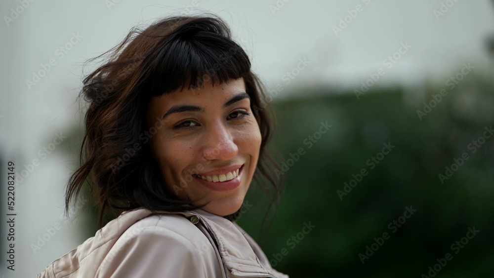 Young woman wearing jacket smiling at camera. A South American latin girl portrait face closeup