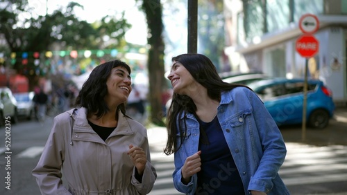 Two happy female friends dancing outside in city street celebrating life. Happy women dancers