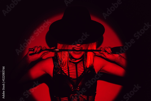 sexy girl in underwear and a hat holds a flogger whip in teeth. BDSM concept of a dominant woman