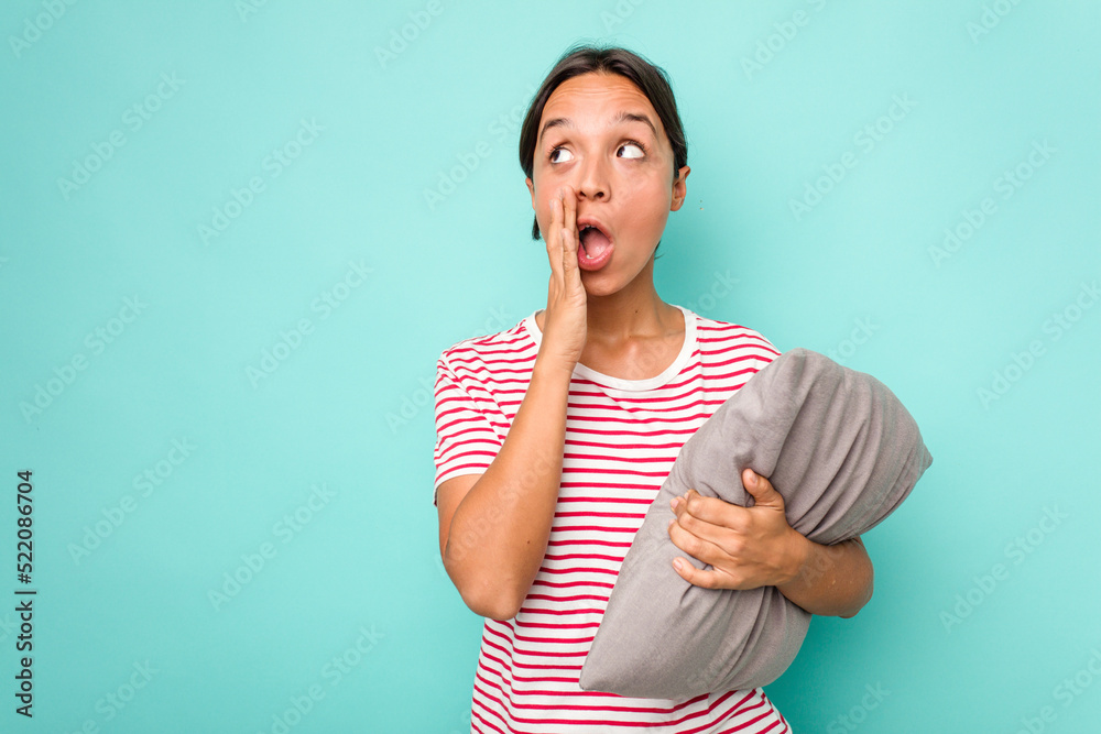 Young hispanic woman holding a cushion isolated on white background is saying a secret hot braking news and looking aside Young hispanic woman holding a cushion isolated on white background is saying a secret hot braking news and looking aside