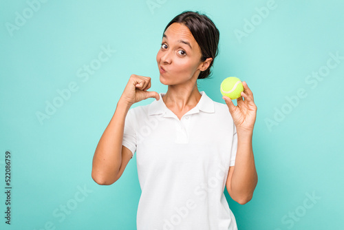 Young hispanic physiotherapy holding a tennis ball isolated on blue background feels proud and self confident, example to follow. © Asier