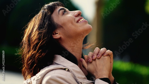 Photos A grateful hispanic woman praying to God with hands clenched looking at sky smiling