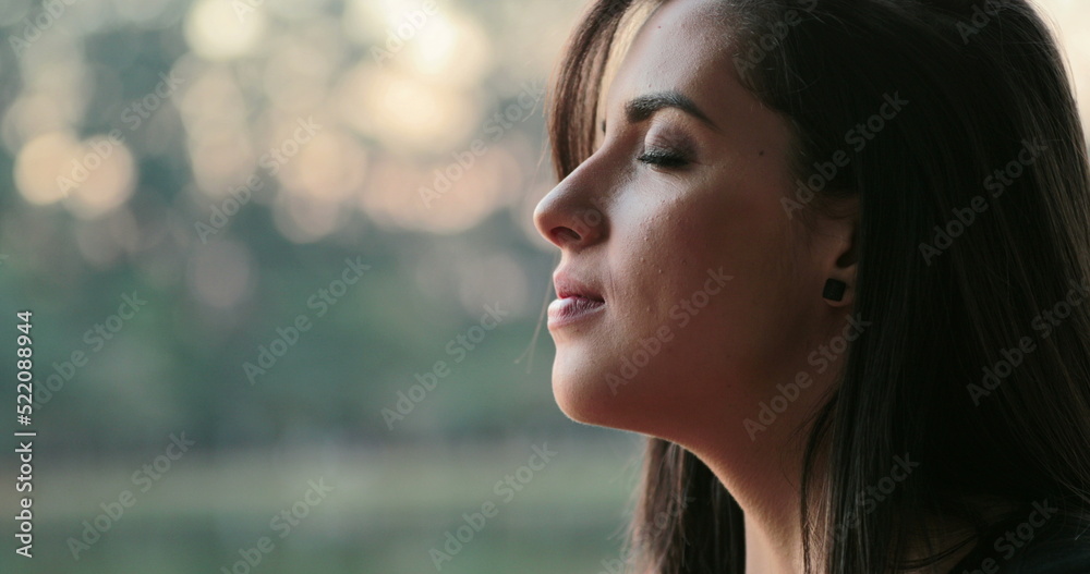 Young woman with eyes closed taking a deep breath outside at the park