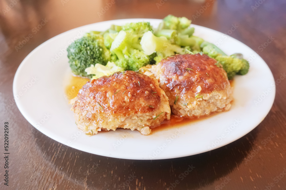 two juicy cutlets with sauce and broccoli on a white plate