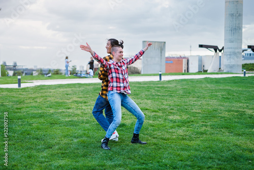 Two young people of different nationalities dancing outdoors in a park