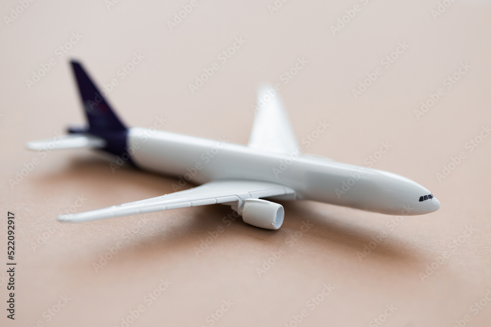 Miniature toy airplane on beige background. Summer holiday air travel by plane concept.